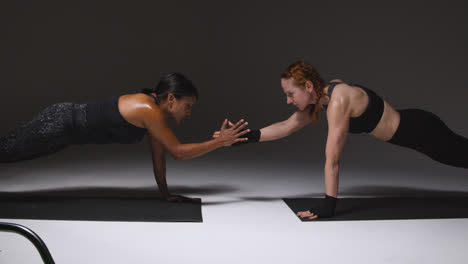 Studio-Shot-Of-Two-Mature-Women-Wearing-Gym-Fitness-Clothing-Doing-Plank-Exercise-Together